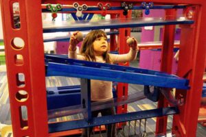 Child playing with the balls and ramps and cause and effect exhibit at the Discovery Museum