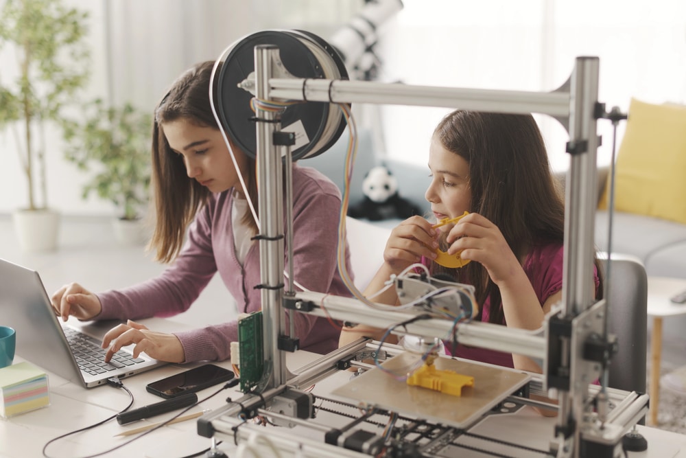 young girls coding and working with a 3D printer